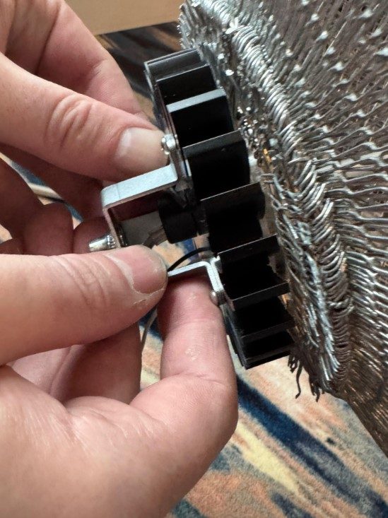 Meshmatics — detail van geweven metaaldraad met messing bol