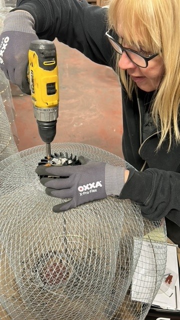 Vakvrouw assembleert een verlichtingsarmatuur met een accuboormachine bij RNDM Production