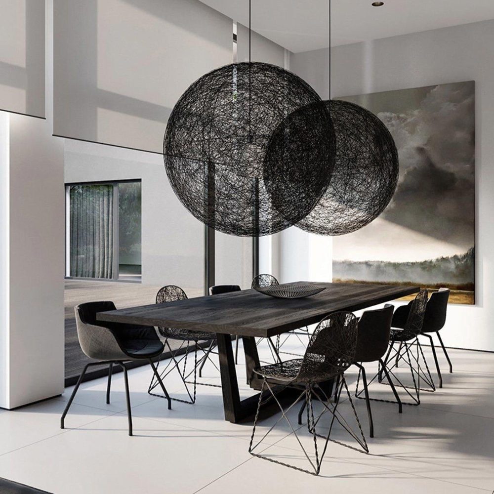 Twee Random Light hanglampen van zwart gewikkeld draad boven een eettafel in een modern interieur